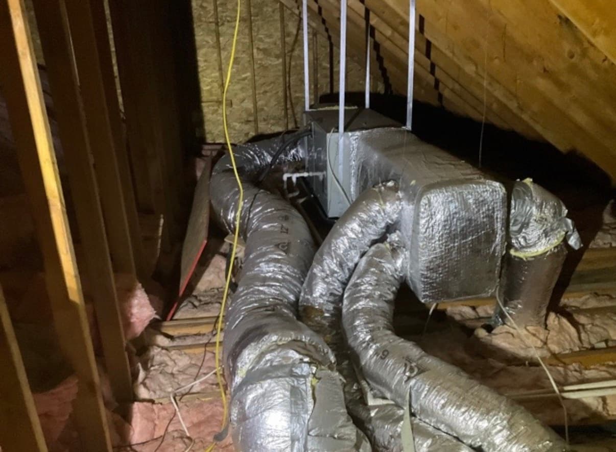 Insulated HVAC supply ducts and air handler in an attic, flagged during a Long Island home inspection